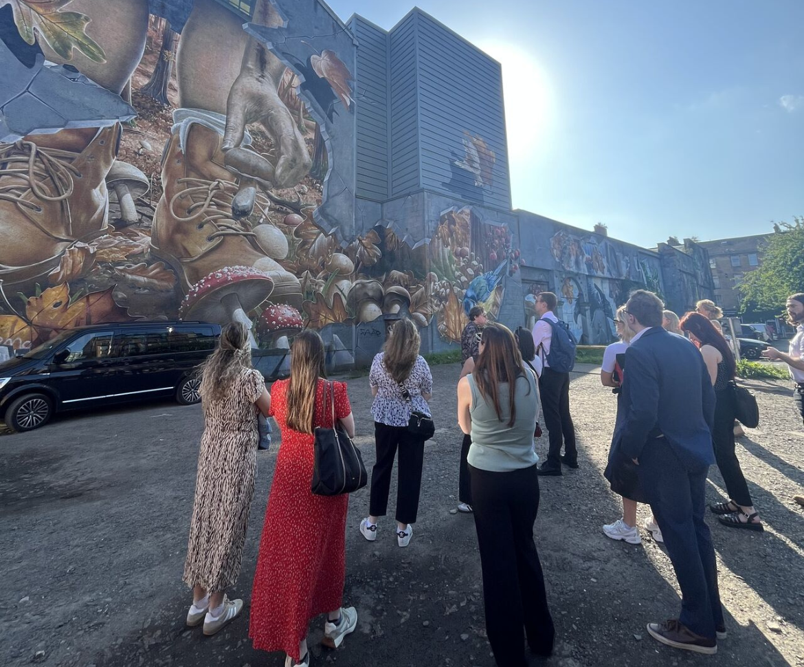 A group at a DWF Link walking tour standing in front of a mural. 