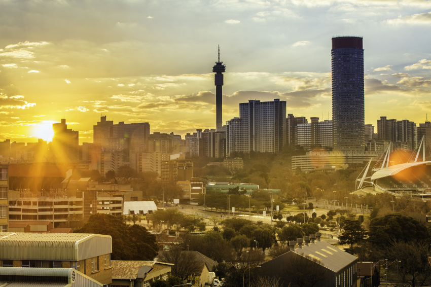 The sun rises behind a Johannesburg cityscape